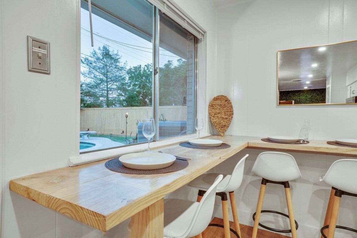 A dining area with a wooden table, white chairs, and a large window with a view of a backyard.