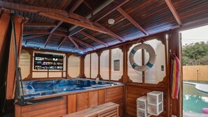 Un'area con vasca idromassaggio, pareti in legno, una panca e un pannello di controllo.