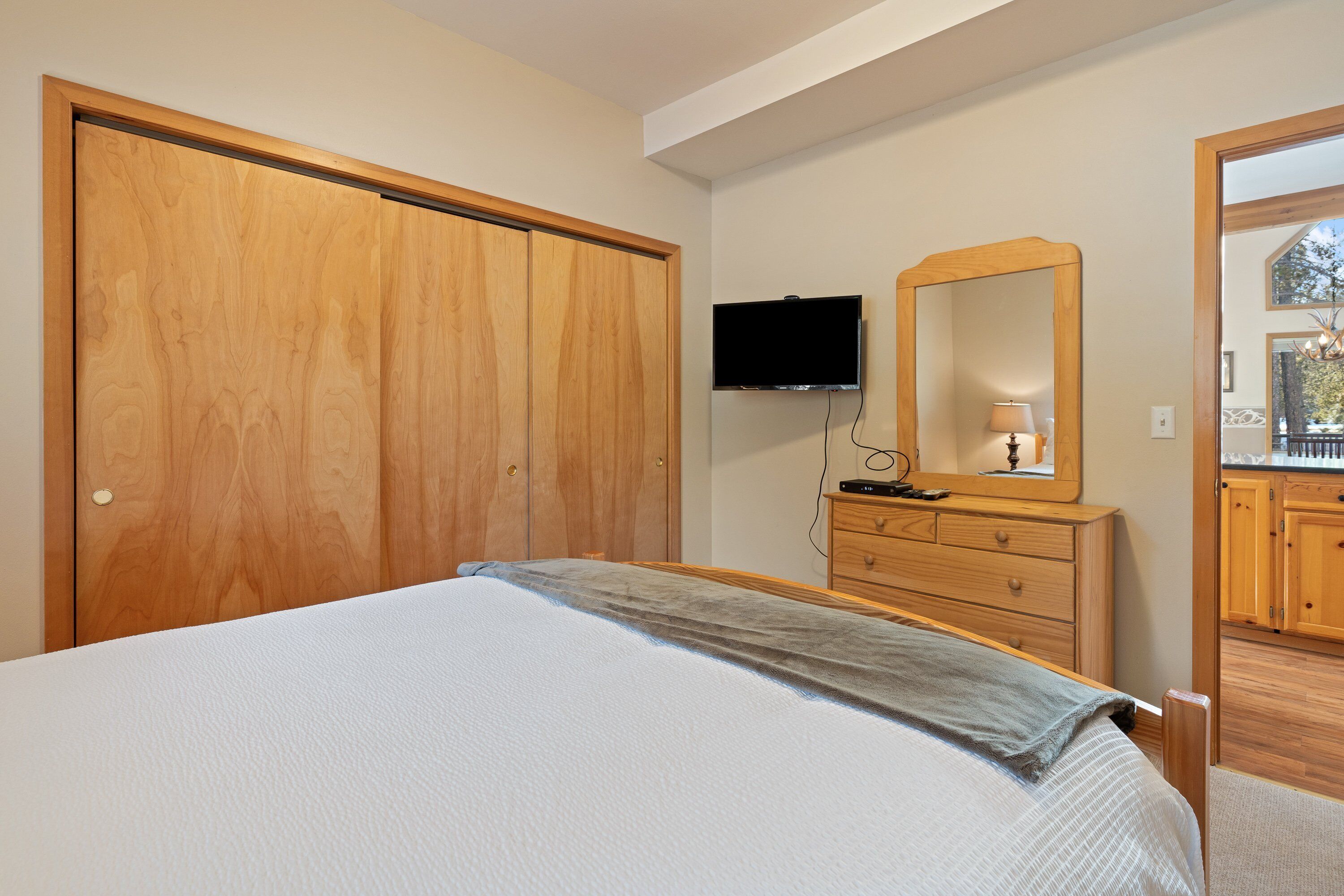 Un dormitorio con cama, armario de madera, cómoda, televisor y espejo.