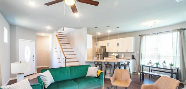 Eine moderne Wohnung mit einem grünen Sofa, einem Essbereich, einer Küche und einer Treppe.