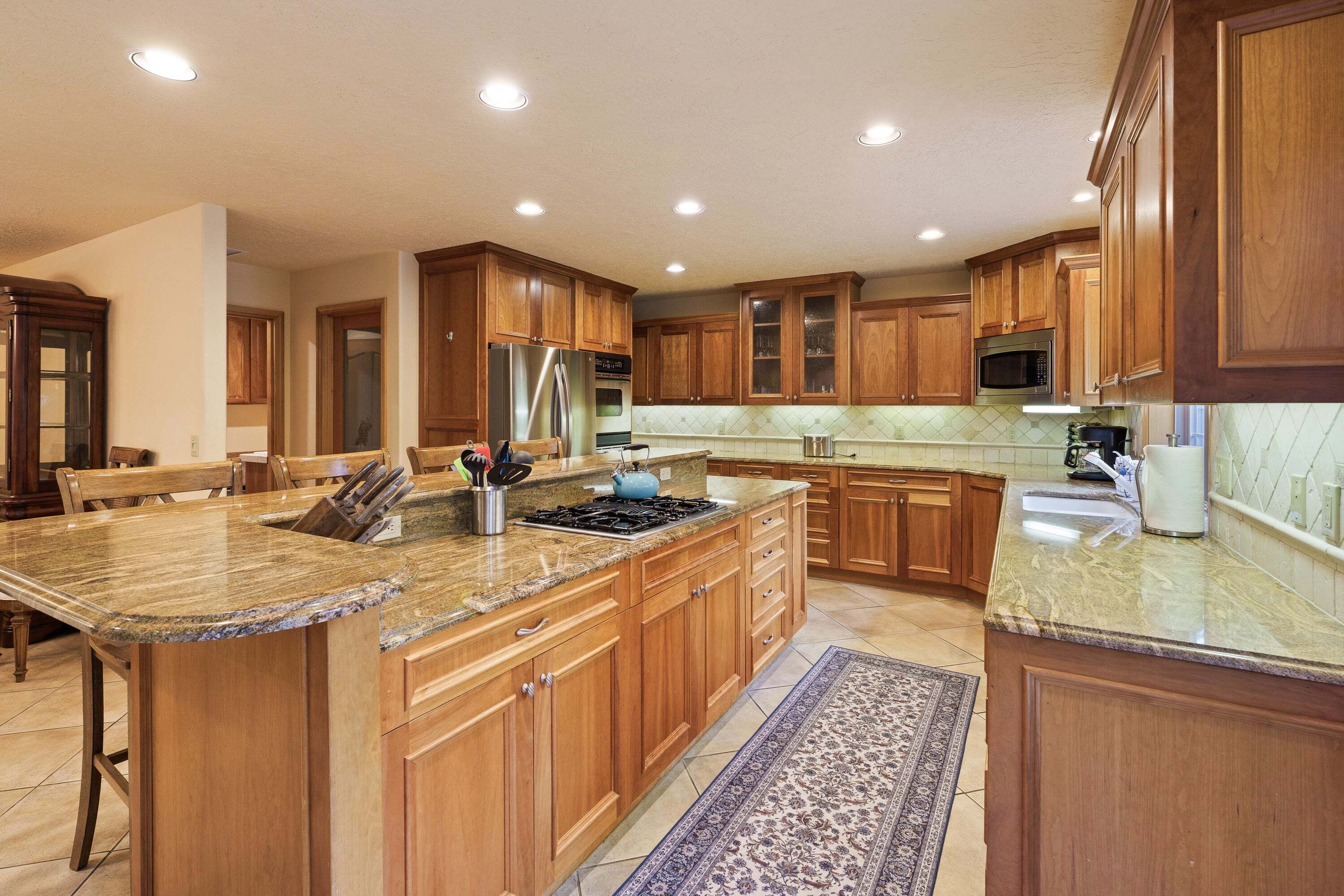 A spacious kitchen with wooden cabinets, granite countertops, stainless steel appliances, and a large island.