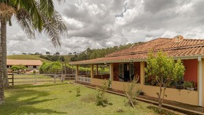 Une maison avec un toit en tuiles, une véranda et une cour clôturée.
