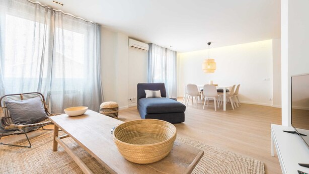 Een moderne woonkamer met een bank, eettafel en televisie.