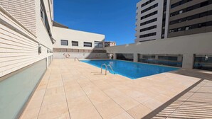 Un espace piscine aménagé sur le toit, doté d’un sol carrelé et d’une piscine à l’eau d’un bleu limpide.