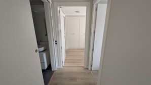 Un couloir avec des toilettes sur la gauche, une porte au fond et un plancher en bois.
