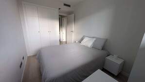 Une chambre à coucher avec un grand lit, une table de chevet, une armoire et une porte donnant sur une autre pièce.