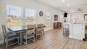 Una cocina amplia con una isla central, ventanas grandes y un comedor con sillas.