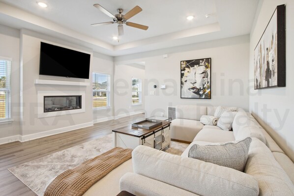 A modern living room with a flat-screen TV, fireplace, sofa, and artwork. - 95070 Gina Street (Fremont)