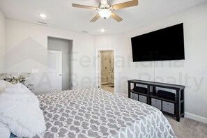 A bedroom with a bed, a ceiling fan, a TV mounted on the wall, and a door leading to a bathroom. - 95070 Gina Street (Fremont)