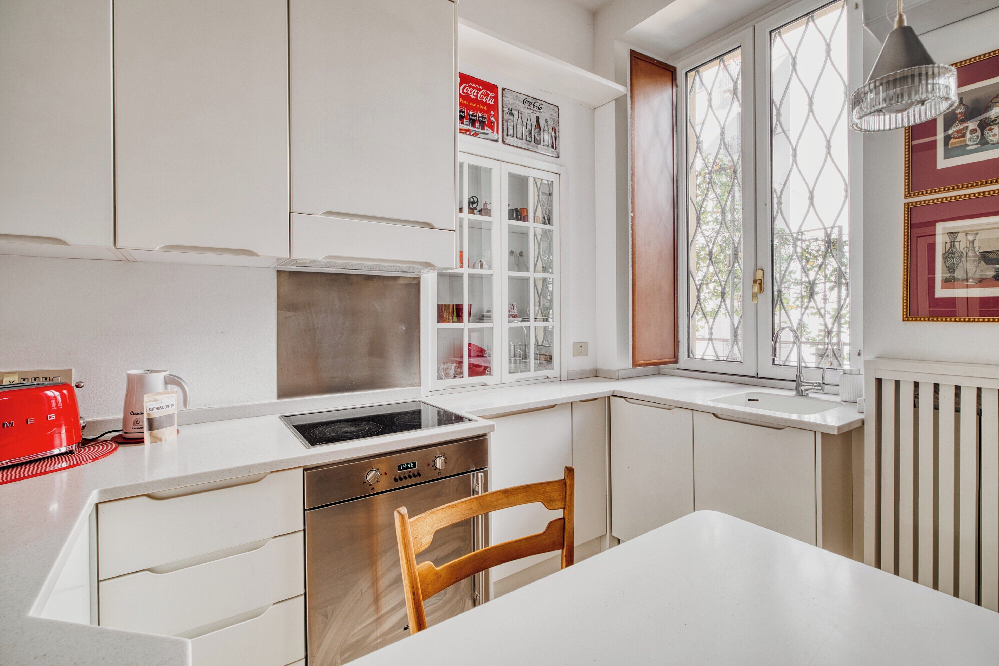 A modern kitchen with white cabinetry, a built-in oven, and a window with a view.