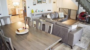 Una sala moderna con una mesa de comedor de madera, un sofá gris y una escalera.