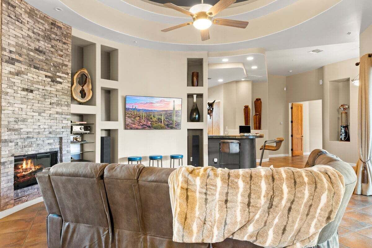 Un salon moderne doté d’une cheminée, d’un ventilateur de plafond, d’un coin cuisine et d’un espace repas.