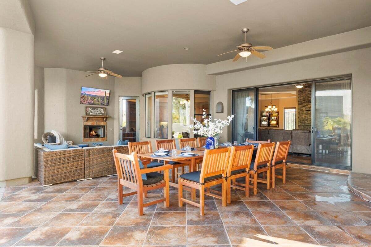 A spacious patio with a dining table, chairs, and a fireplace.