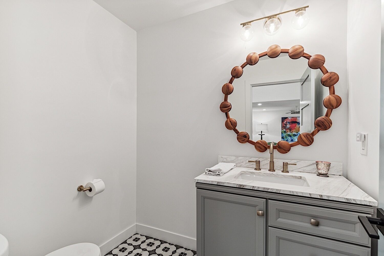 A bathroom with a round mirror, a sink, and a toilet.