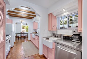 A kitchen with pink cabinets, a stainless steel refrigerator, and a coffee maker. - Cardillo 3 (Palm Springs)