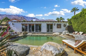 A pool area with lounge chairs, a white building with large windows, and a mountain backdrop. - Cardillo 3 (Palm Springs)