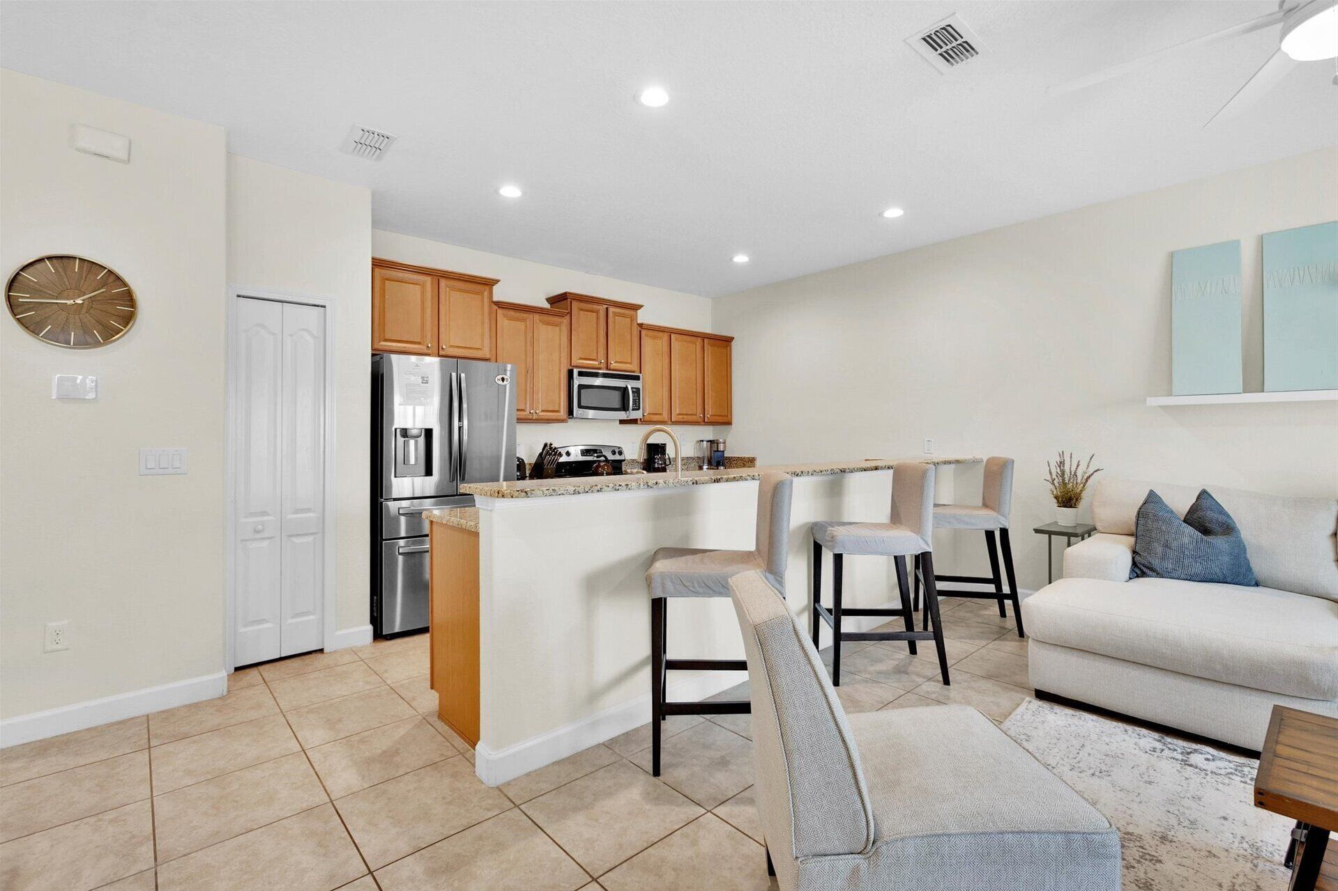 A modern kitchen with wooden cabinets, stainless steel appliances, and a central island with bar stools.