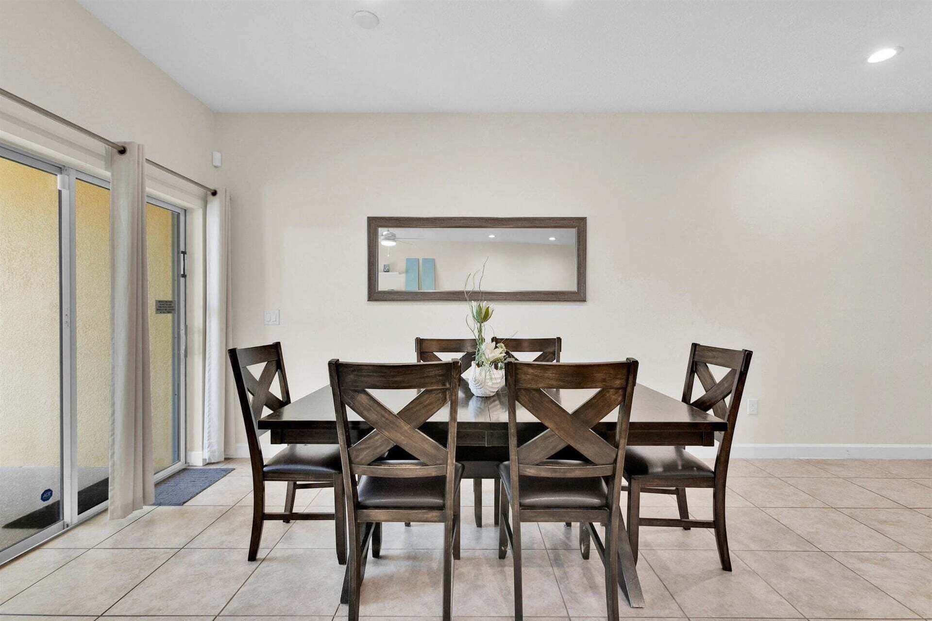 A dining area with a table and chairs, a mirror on the wall, and a door with glass panels.