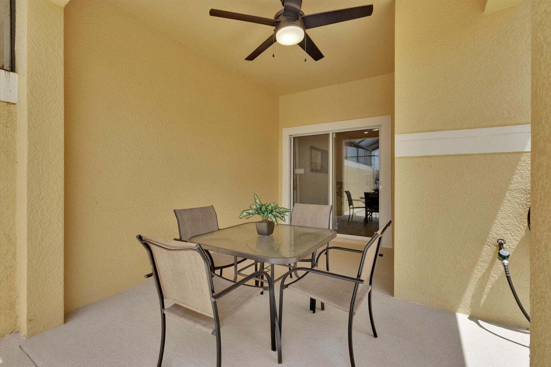 A dining area with a table, chairs, a ceiling fan, and a potted plant.