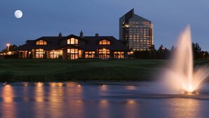 Un grande hotel con diversi edifici, una piscina ben visibile con una fontana e una luna nel cielo.