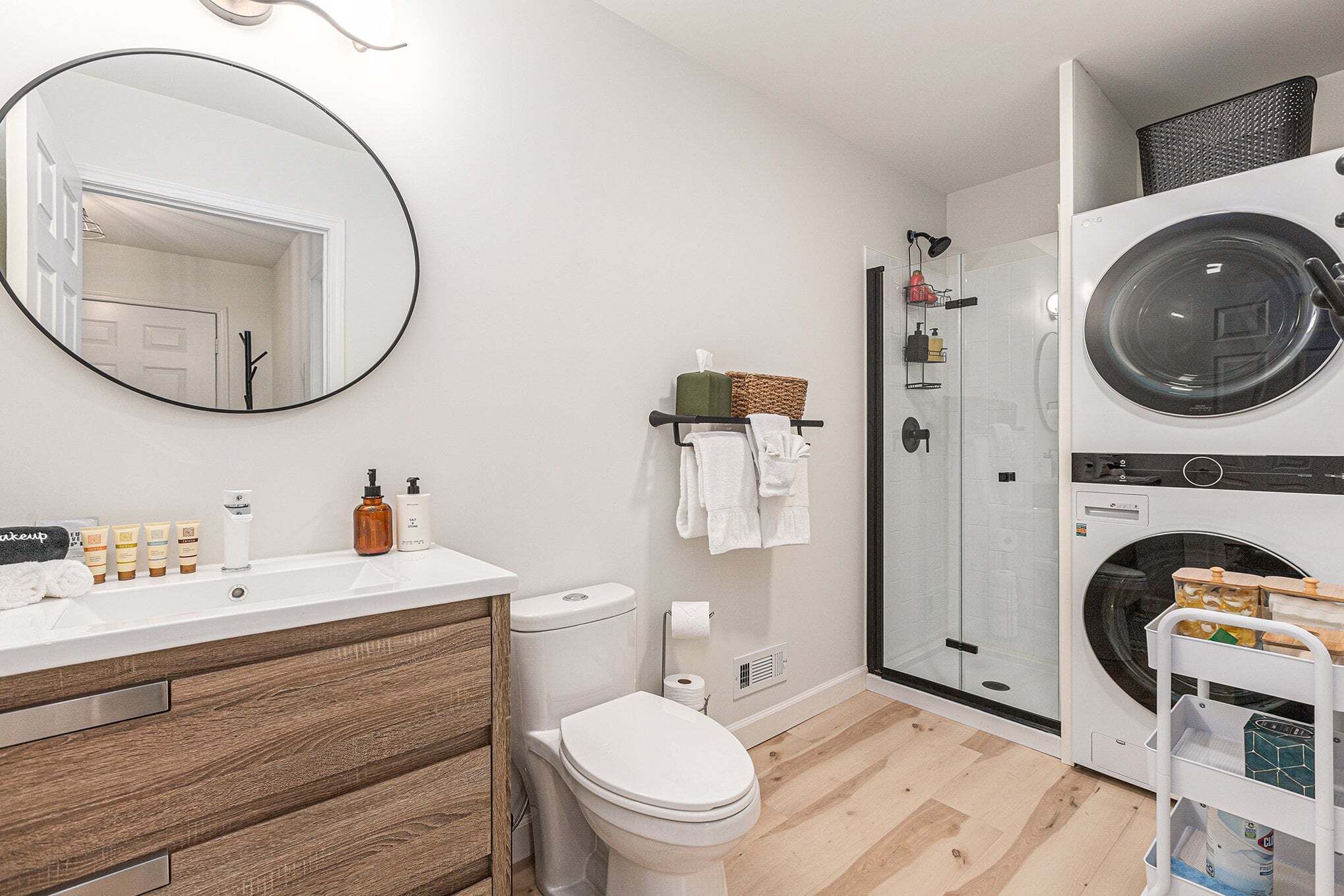 Un baño moderno con inodoro, lavamanos, espejo y lavadora.
