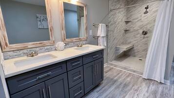 A bathroom with two sinks, a large mirror, and a shower area.