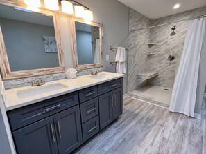 Une salle de bain avec deux lavabos, un grand miroir et un espace douche.