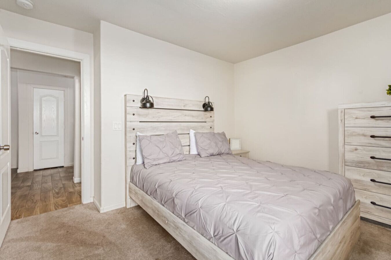 A bedroom with a bed, a dresser, and a door.