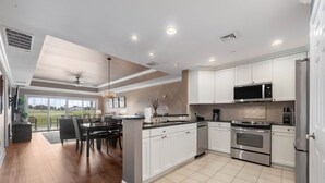 A modern kitchen with white cabinets, stainless steel appliances, and a dining area with a view of the outdoors. - Di0103 Centre Court Amore (Kissimmee)