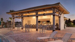 An outdoor pool area with lounge chairs, a covered seating area, and a poolside bar. - Dazzing 9BR Pool Spa Free Waterpark (Davenport)