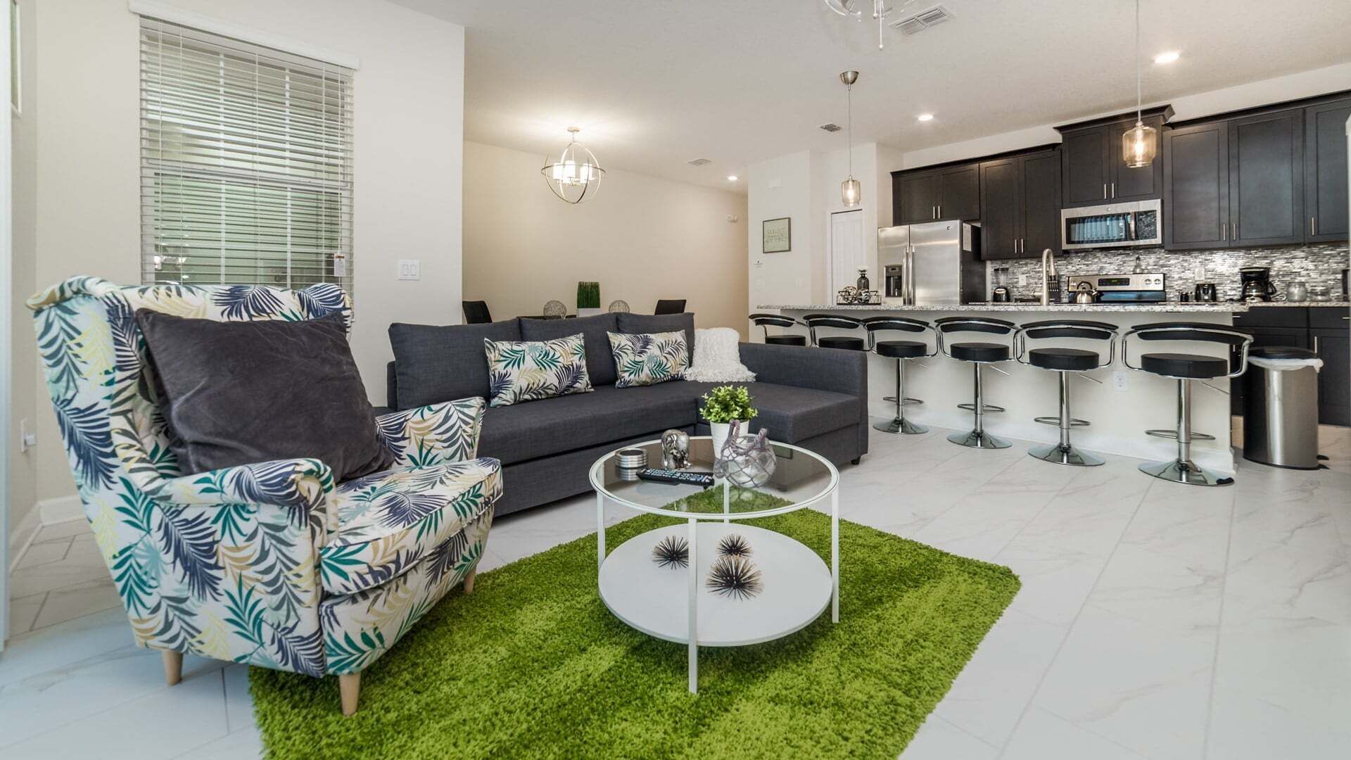 Una sala de estar moderna con sofá, una mesa de centro y una cocina con taburetes de bar.
