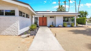 A modern two-story house with a concrete pathway leading to a red door. - Avery (Palm Springs)