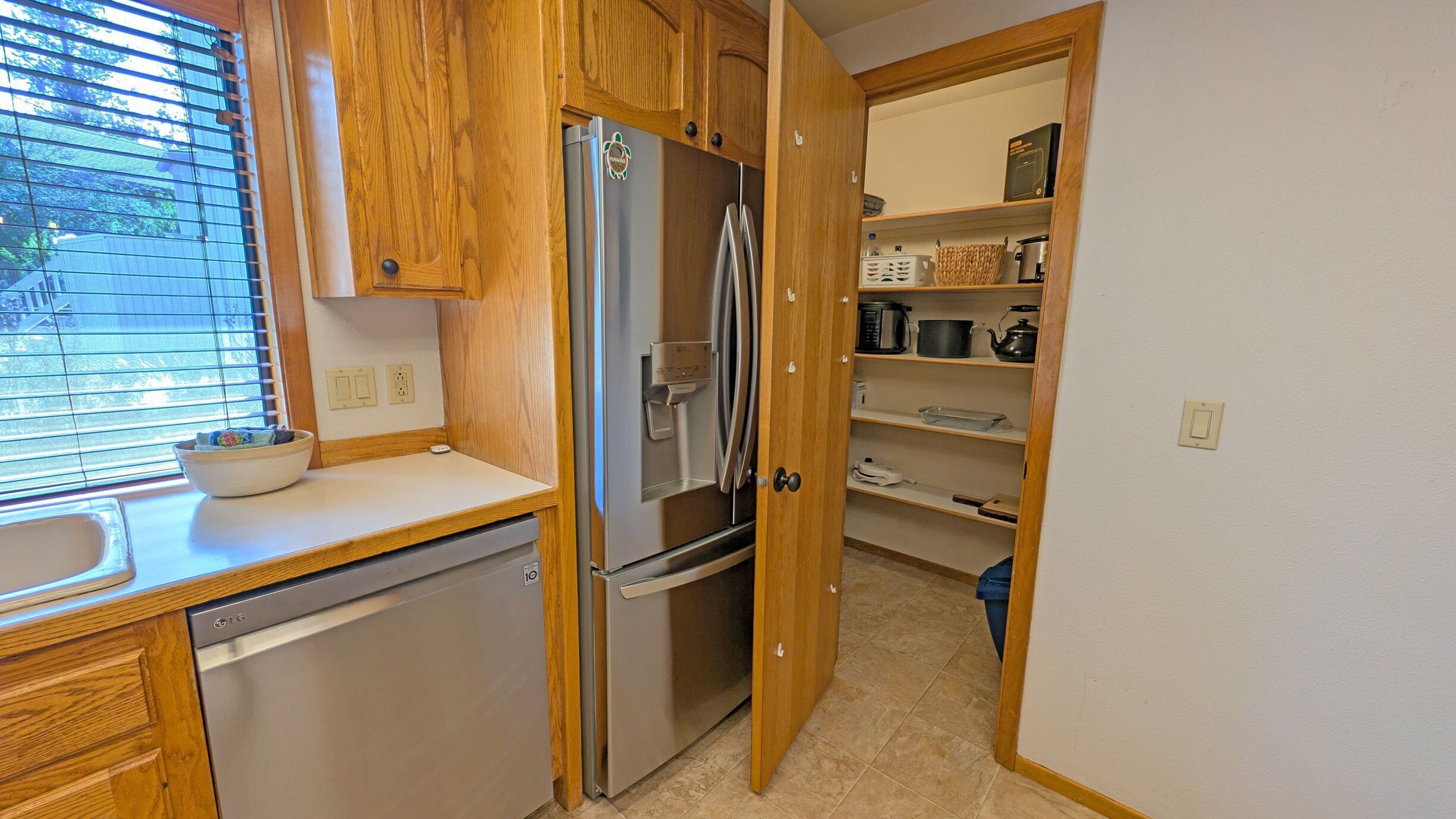A compact kitchen with wooden cabinets, a stainless steel refrigerator, and a dishwasher.