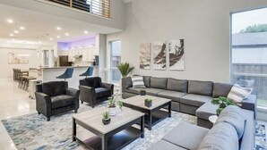 A spacious living area with a high ceiling, a dining area, and a kitchen.