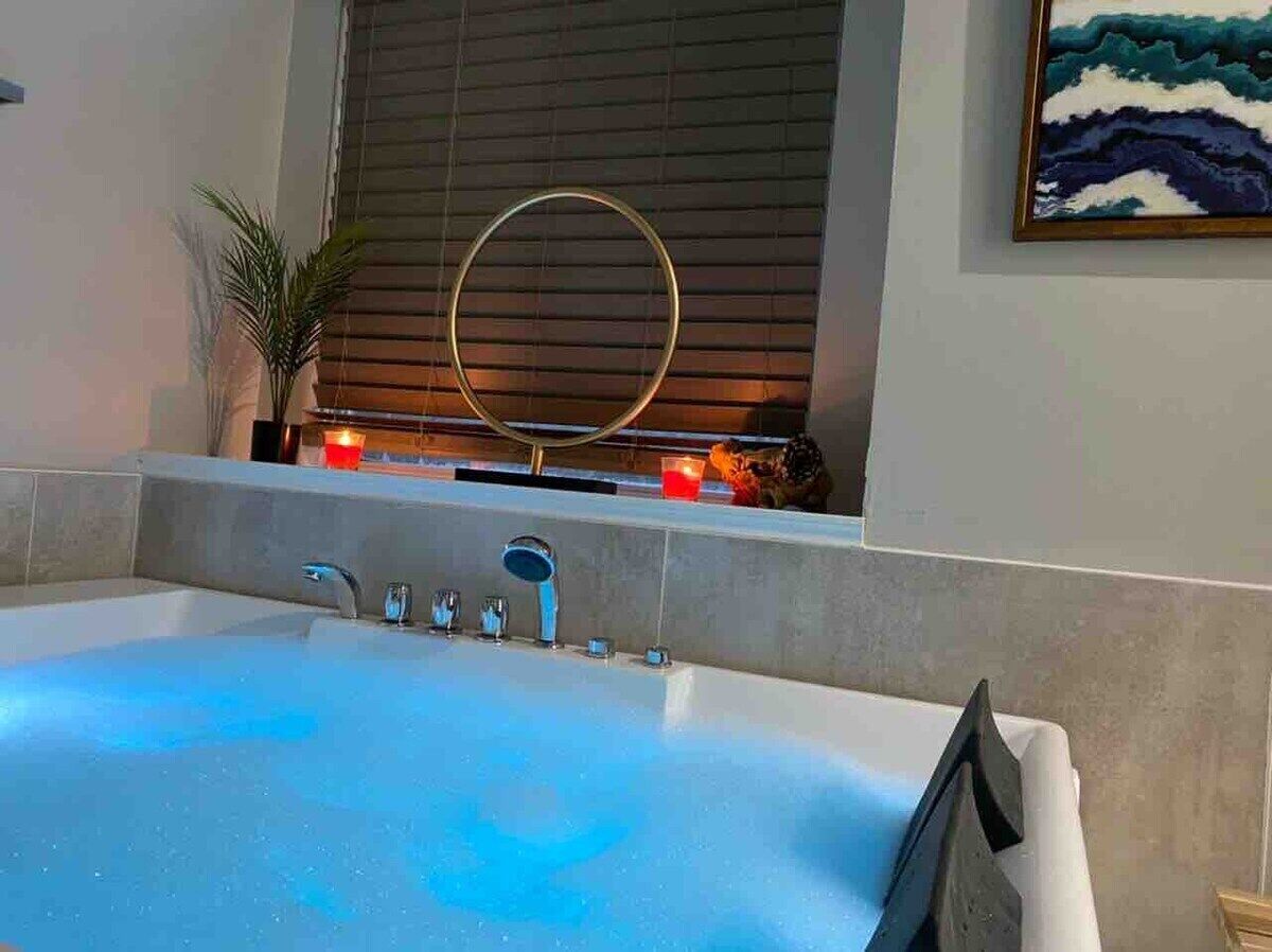 Un bagno moderno con una vasca da bagno ampia, uno specchio rotondo e un quadro raffigurante onde sulla parete.
