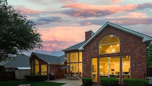 A brick house with large windows and a swimming pool.