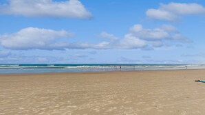 A wide sandy beach with a clear blue sky and scattered clouds. - Daytona Beach Retreat (Daytona Beach)