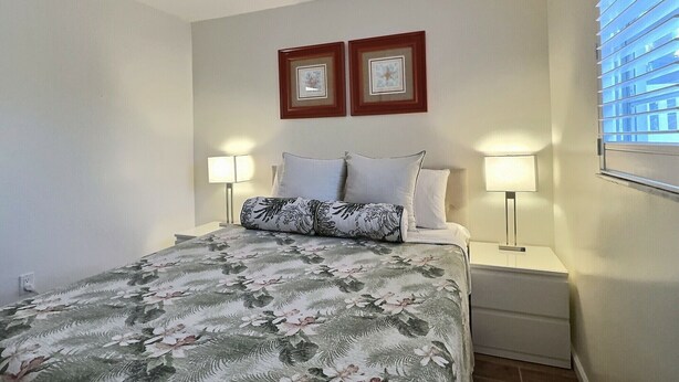 Una camera da letto con un letto, due lampade da comodino, una ventola a soffitto e due quadri appesi al muro.