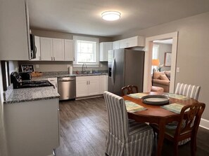 A compact kitchen with a dining area, a refrigerator, a stove, and a window. - Historic Home in Downtown Greer Shop,eat & Sleep (Greer)