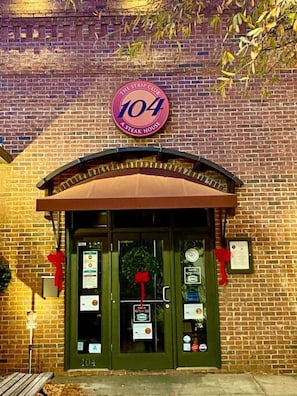 A brick building with a sign reading 'The Strip Club 104 A Steak House.' - Historic Home in Downtown Greer Shop,eat & Sleep (Greer)