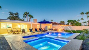A swimming pool with lounge chairs and umbrellas, surrounded by a landscaped garden and a building with large windows. - Eugie Terrace Scottsdale (Scottsdale)