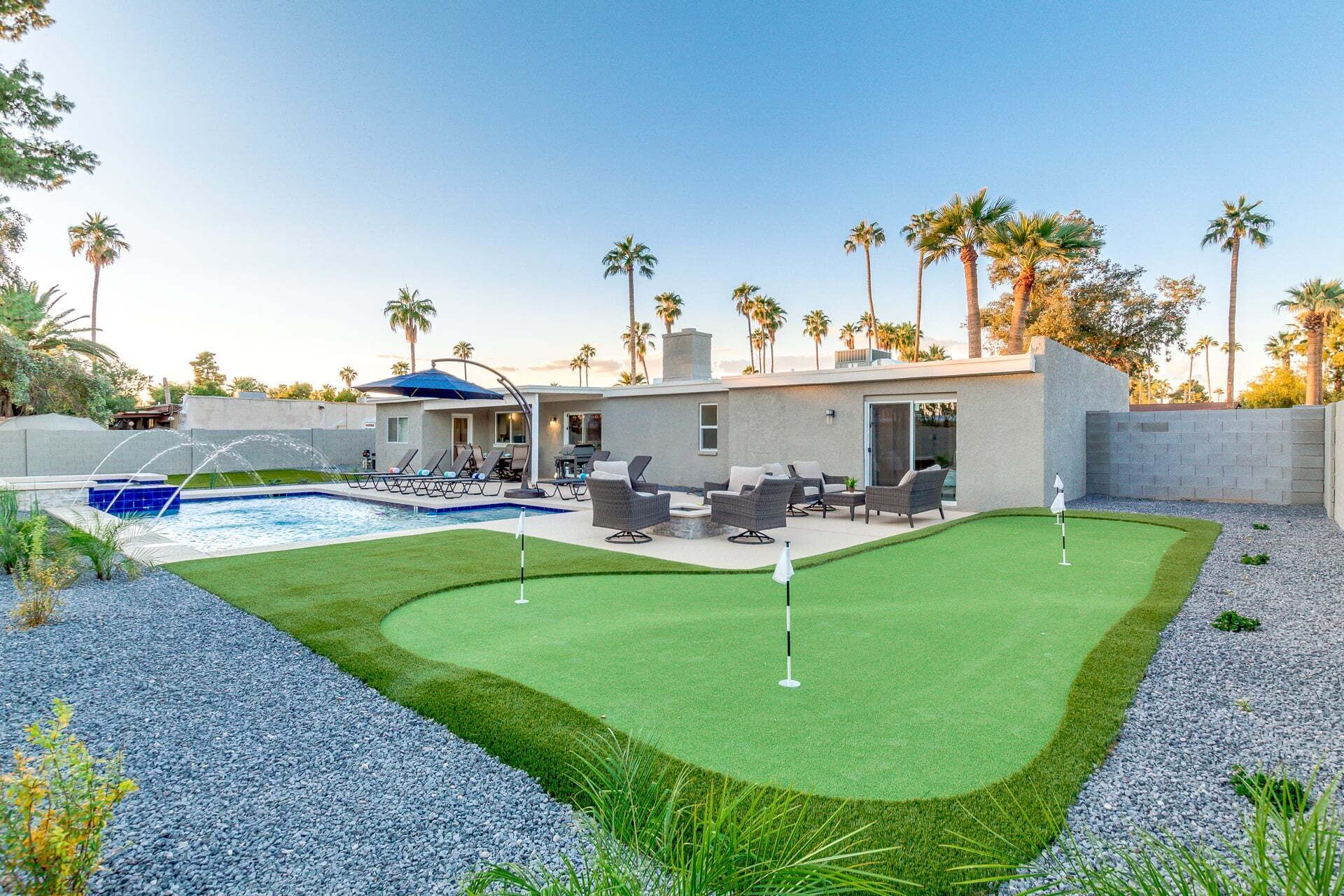 A modern house with a swimming pool, a patio with outdoor furniture, and a well-maintained lawn.