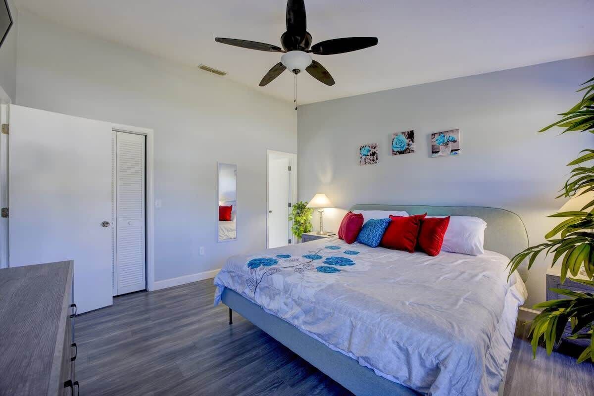 Ein Schlafzimmer mit Bett, Deckenventilator, Tür und Wandbildern.
