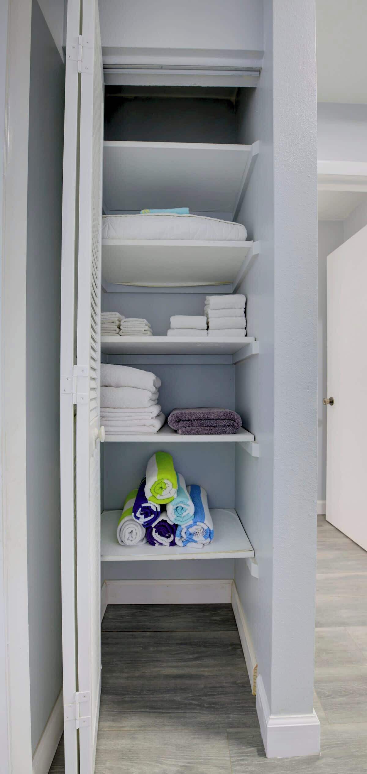 A walk-in closet with multiple shelves for folded towels and linens.