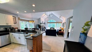 A spacious kitchen with a large island, white cabinetry, and a fireplace. - Fv43 Bretton Woods Single Level Home With AC on Golf Course! (Rye)