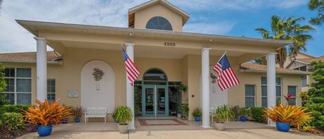 A building with a beige facade, a clock, and two American flags.