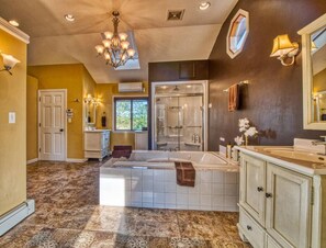 A spacious bathroom with a large bathtub, a walk-in shower, and a vanity with a mirror. - Elyon Hall + Coach House (Gary)