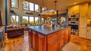 A spacious kitchen with wooden cabinets, a large island, and a view of the outdoors. - Elyon Hall + Coach House (Gary)