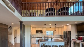 A spacious kitchen with a central island, wooden flooring, and a view of the upper level. - Elyon Hall + Coach House (Gary)
