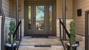 A front entrance with a double door, a small porch area, and two potted plants on either side. - Elyon Hall + Coach House (Gary)